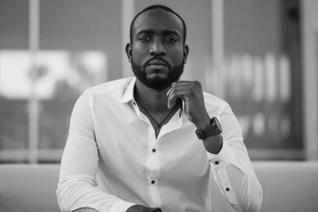 Black and white portrait of a stylish man in a white shirt indoors.