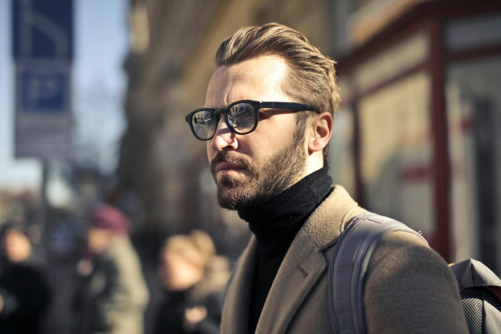 A fashionable man with glasses walks through the vibrant streets of Budapest, Hungary.